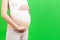 Close up of pregnant woman dressed in orthopedic corset for reducing pain in the back at green background with copy space.