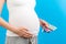 Close up of pregnant woman holding different blisters with pills at colorful background with copy space. Taking supplement during