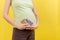 Close up of pregnant woman holding maternal supplements at colorful background with copy space. Pills in blisters. Health care