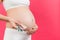 Close up of pregnant woman holding maternal supplements at colorful background with copy space. Pills in blisters. Health care