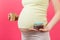 Close up of pregnant woman holding a paper cup and a heap of blisters with pills at colorful background with copy space. Treatment