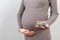 Close up of pregnant woman holding a pile of blisters of pills at colorful background with copy space. Vitamins during pregnancy