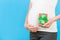 Close up of pregnant woman in home clothing holding gift box at blue background. Baby surprise concept. Happy pregnancy. Copy