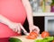 Close up pregnant woman with knife on kitchen cuts