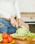 Close up pregnant woman with knife on kitchen cuts salad