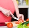 Close up pregnant woman with knife on kitchen cuts vegetables