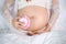 Close-up pregnant woman listening to fetal heart sound through headphones on bed