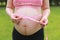 Close-up of pregnant woman mother belly, she is using a ruler to measure waistline keep healthy do exercise