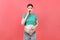 Close up of a pregnant woman in opened jeans measuring her belly with a tape measure at colorful background with copy space.