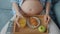 Close-up of pregnant woman`s belly and hands enjoying healthy meal and watching TV at home