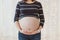 Close-up of pregnant woman`s big hairy belly on bright bokeh lights background