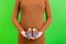 Close up of pregnant woman showing small boots for a baby boy at green background. Future mother is waiting for a child. Copy