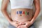 Close up Pregnant woman sitting on soft sofa and touching her belly with sign FEMALE in front of her belly