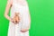 Close up of pregnant woman in white dress holding teddy bear against her abdomen at green background. Parenthood concept. Copy