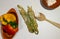 Close up preparation pasta tagliatelle with pesto. Flour, yellow and red peppers and wooden spoon on white background