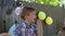 Close up of preschool boy in birthday hat eating cake with hands outdoors. Kids birthday party.