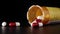 Close up of a prescription pill bottle tipping over with red and white pill capsules falling out. Concept for addiction,