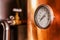 Close up of a pressure gauge inside of a modern beer plant brewery with vessels, tubs and pipes made of stainless steel