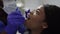 Close-up of pretty african young woman patient being examined by male african american doctor dentist in blue suit and