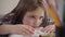 Close-up of pretty caucasian brunette girl with brown eyes holding head on book. Tired schoolgirl looking away resting