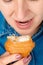 Close-up of a pretty Caucasian woman with her mouth open holding a bitten croissant in front of her. In front from a high angle