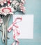 Close up of pretty flowers on turquoise blue shabby chic background and mock up of greeting card with pink ribbon