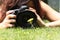 Close up of a pretty girl taking a photograph of a flower on the grass