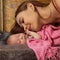 Close-up pretty woman kisses a newborn baby in her arms