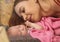 Close-up pretty woman kisses a newborn baby in her arms