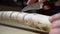 Close up process of man making wooden walking stick indoors during quarantine. Carving wood stick on the table using knife