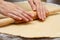 Close up of process woman rolling pin rolls dough on a table with flour