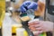 Close-up of Professional barista hands, preparing hot milk foam, pourin milk in paper cup with coffee cappuccino. Coffee