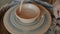 Close-up of professional ceramist decorating bowl with tools working on pottery wheel