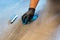 Close up of professional cleaner cleaning grout with a blue cloth rag and foamy soap on a gray tiled bathroom floor