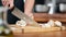 Close-up professional cook person hand slicing mushrooms on wooden board. Wide shot on RED camera