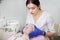 Close up of professional doctor dermatologist in blue rubber gloves, applying film on the face of teen girl patient with