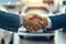 Close up of a professional handshake at a car dealership with cars in background