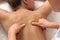 Close-up professional masseuse performing with hand back massage to young woman client in wellness spa center