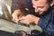 Close-up of a professional windshield repairman fills a crack in the glass with a special polymer through a syringe