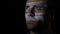 Close up of a programmer software developer working in a dark room while the computer code is reflected on his face -