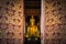 Close up public golden buddha statue looks through entrance door in wat Phra That Chae Haeng public temple at Nan