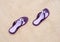 Close-up of purple flip-flops on the sand