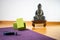 Close up of purple yoga mat with blue yoga band and yoga blocks and buddha statue in the background