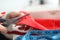 Close-up of qualified female dressmaker cutting red cloth with scissors