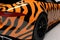 A close up of a race car with a bright orange and black zebra livery. Speed drive concept. AI generation