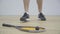 Close-up of racket and ball lying on the floor in gym as unrecognizable Caucasian sportsman coming up and taking