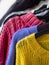 Close up rail of hanger cozy winter knitted jumpers and woolen sweaters in various colors