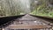 Close up of railway in mountainous terrain. Railway track in rainy weather in amazing and mysterious nature.