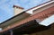 A close-up of a rain gutter with a stop end and running outlet installed correctly a few inches lower than the roofline with a