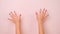 Close-up of raised child hand showing nail polish on pastel pink background in studio. Pack of Gestures movements and body